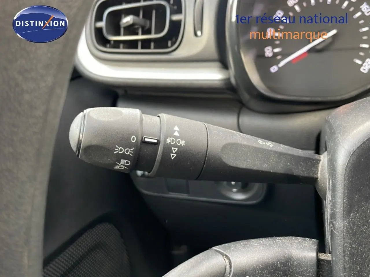 Gros plan sur la commande des feux à gauche du volant d’une Citroën C3 2018, intérieur noir.