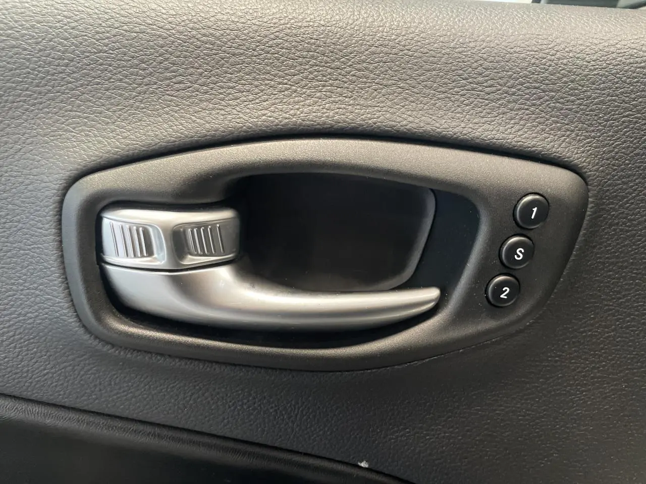 Poignée intérieure de porte noire avec boutons de réglage mémoire des sièges dans une Jeep Compass Trailhawk.