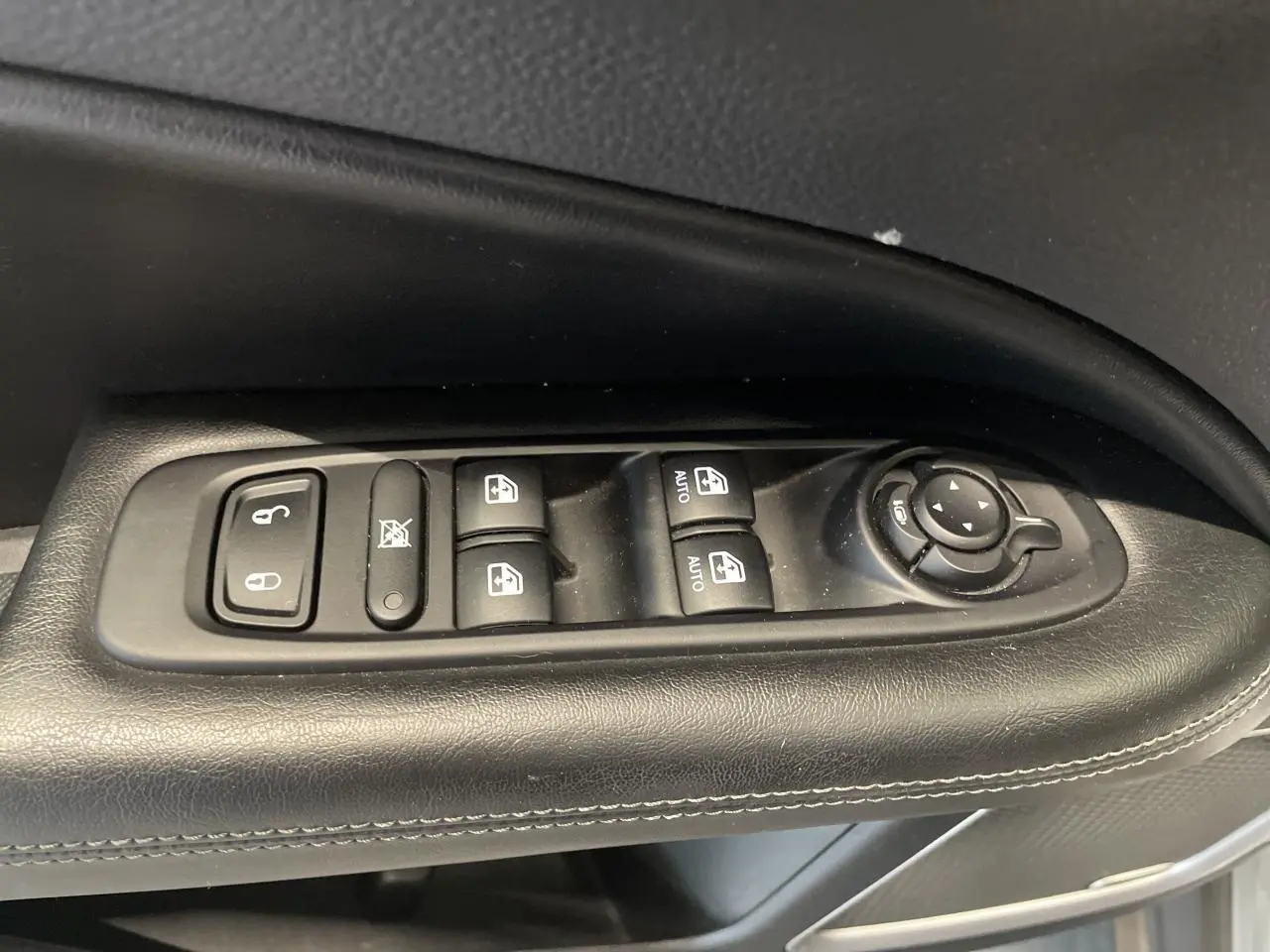 Gros plan sur les commandes électriques des vitres et rétroviseurs sur la porte côté gauche du Jeep Compass gris foncé.