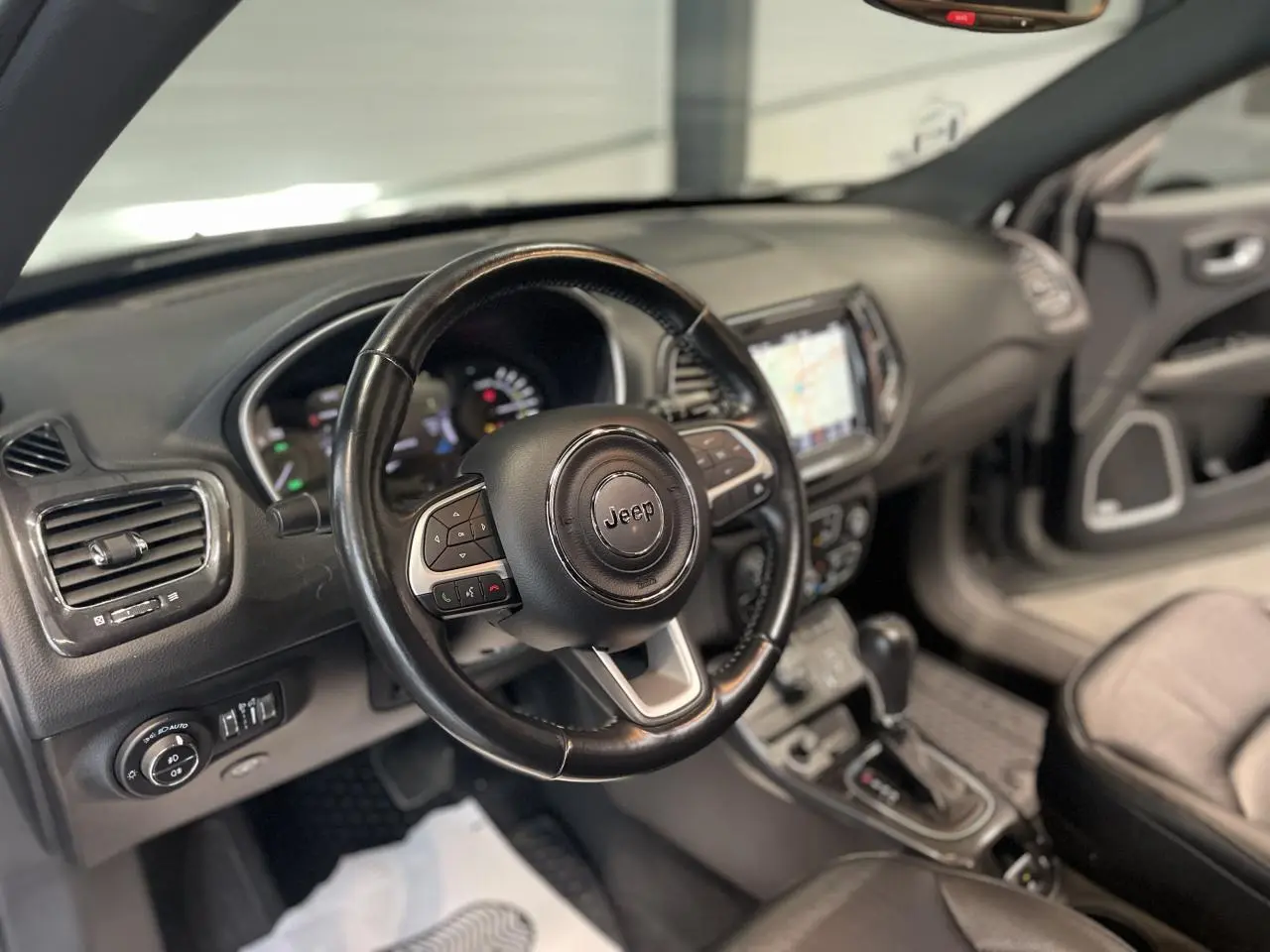 Vue intérieure du volant cuir noir et tableau de bord du Jeep Compass 2021 avec écran tactile et commandes au volant.