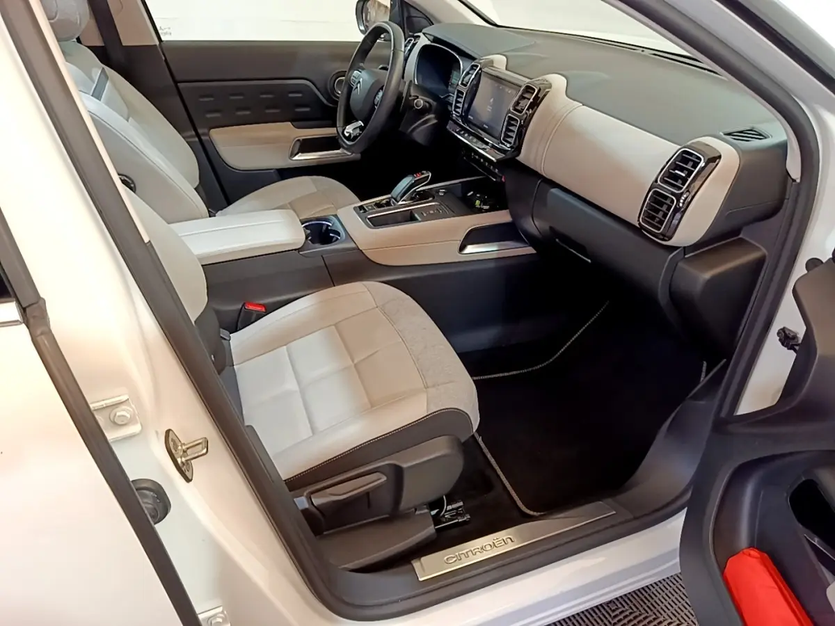 Vue intérieure côté conducteur du Citroën C5 Aircross blanc, montrant sièges bicolores et tableau de bord moderne avec écran tactile.