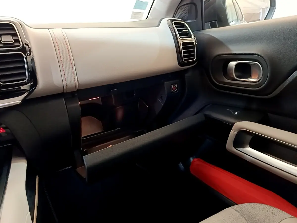 Intérieur côté passager du Citroën C5 Aircross Hybrid blanc, tableau de bord clair et boîte à gants ouverte.
