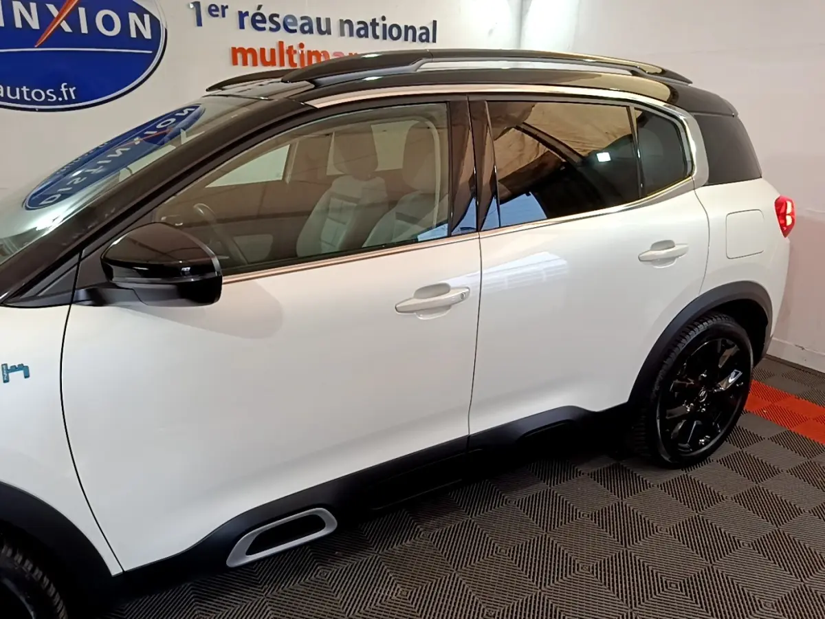 Vue de profil côté gauche d'un Citroën C5 Aircross Hybrid blanc avec toit noir et jantes noires.