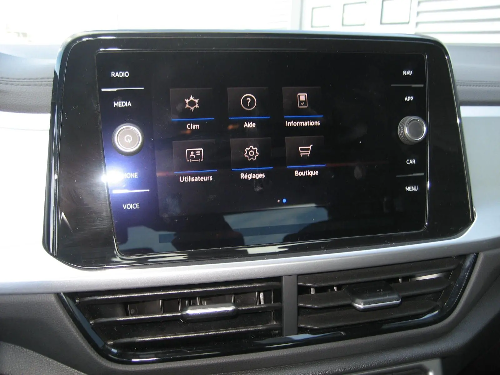 Écran tactile central du Volkswagen T-Roc 2023 affichant le menu principal avec commandes climatisation et réglages.