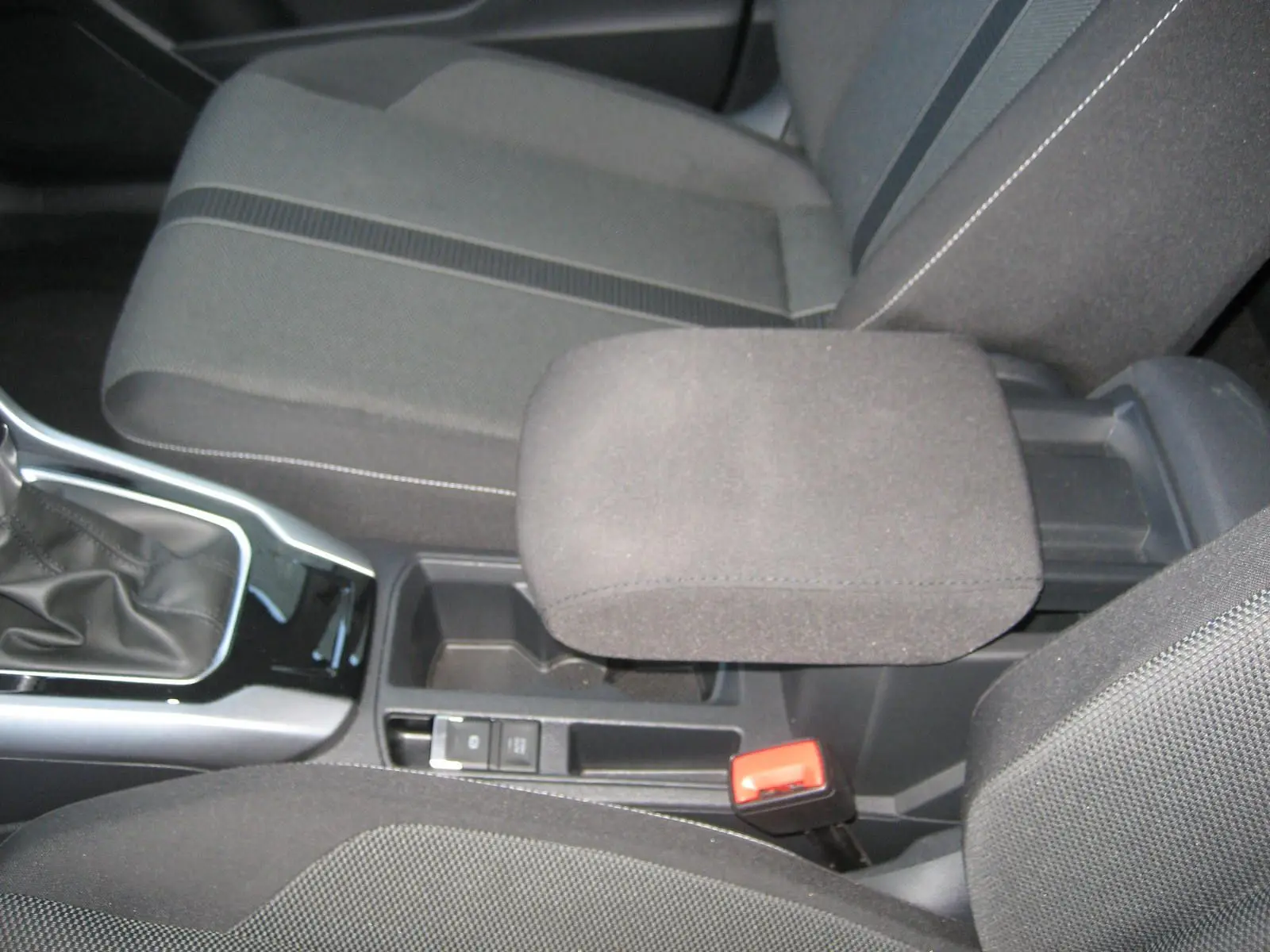Vue intérieure rapprochée du levier de vitesse et accoudoir central en tissu gris foncé du Volkswagen T-Roc 2023.