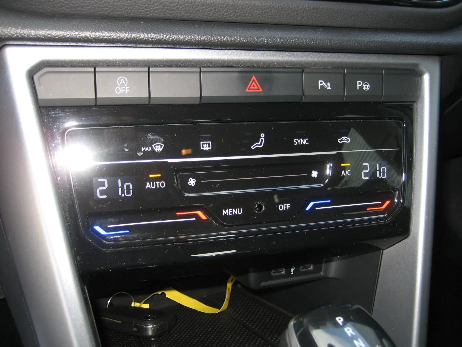 Gros plan sur la console centrale du Volkswagen T-Roc gris clair 2023, affichant la climatisation digitale et la boîte automatique.