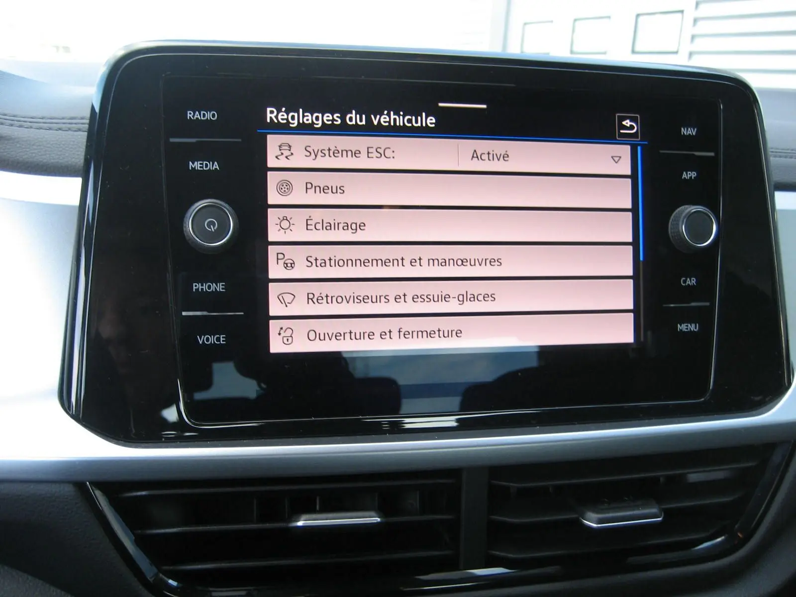 Écran tactile central du Volkswagen T-Roc 2023 affichant les réglages du véhicule dans un intérieur moderne.