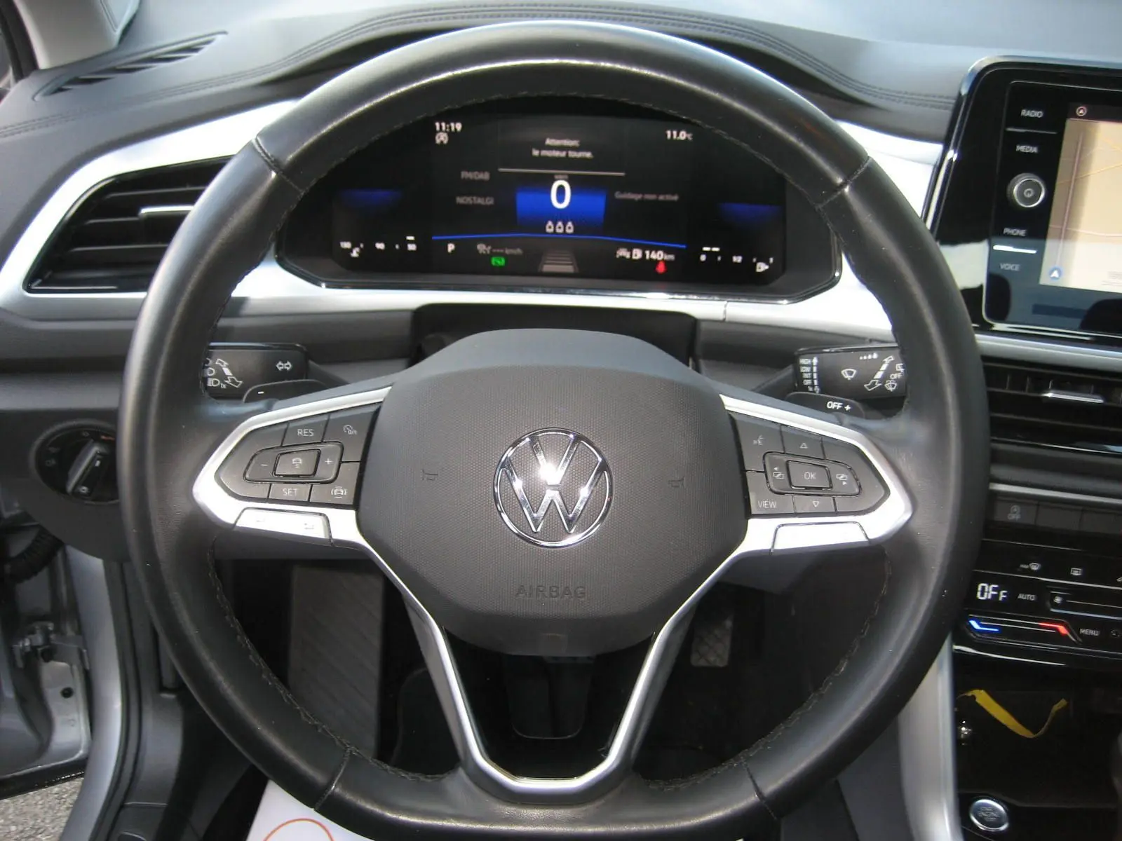 Vue rapprochée du volant noir du Volkswagen T-Roc 2023 avec tableau de bord numérique et écran tactile visible.