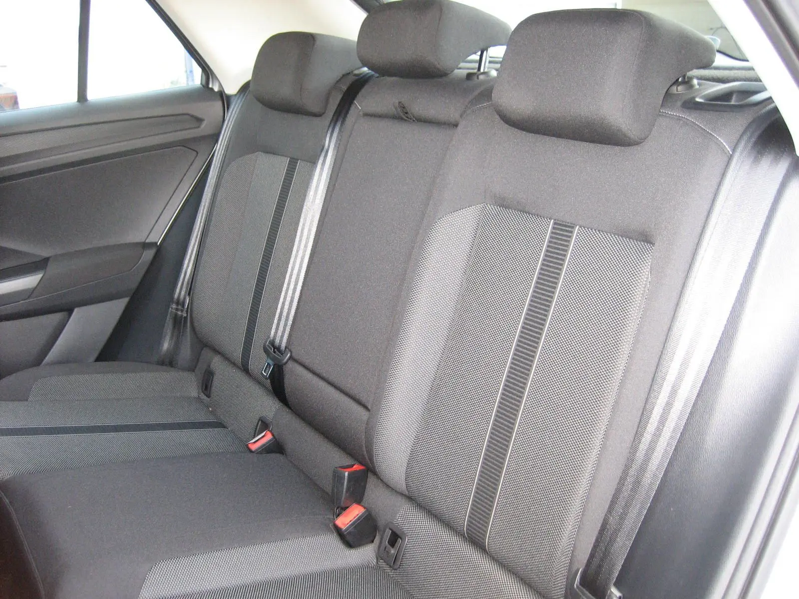 Vue intérieure montrant la banquette arrière grise foncée du Volkswagen T-Roc 1.5 TSI 2023 avec ceintures de sécurité visibles.