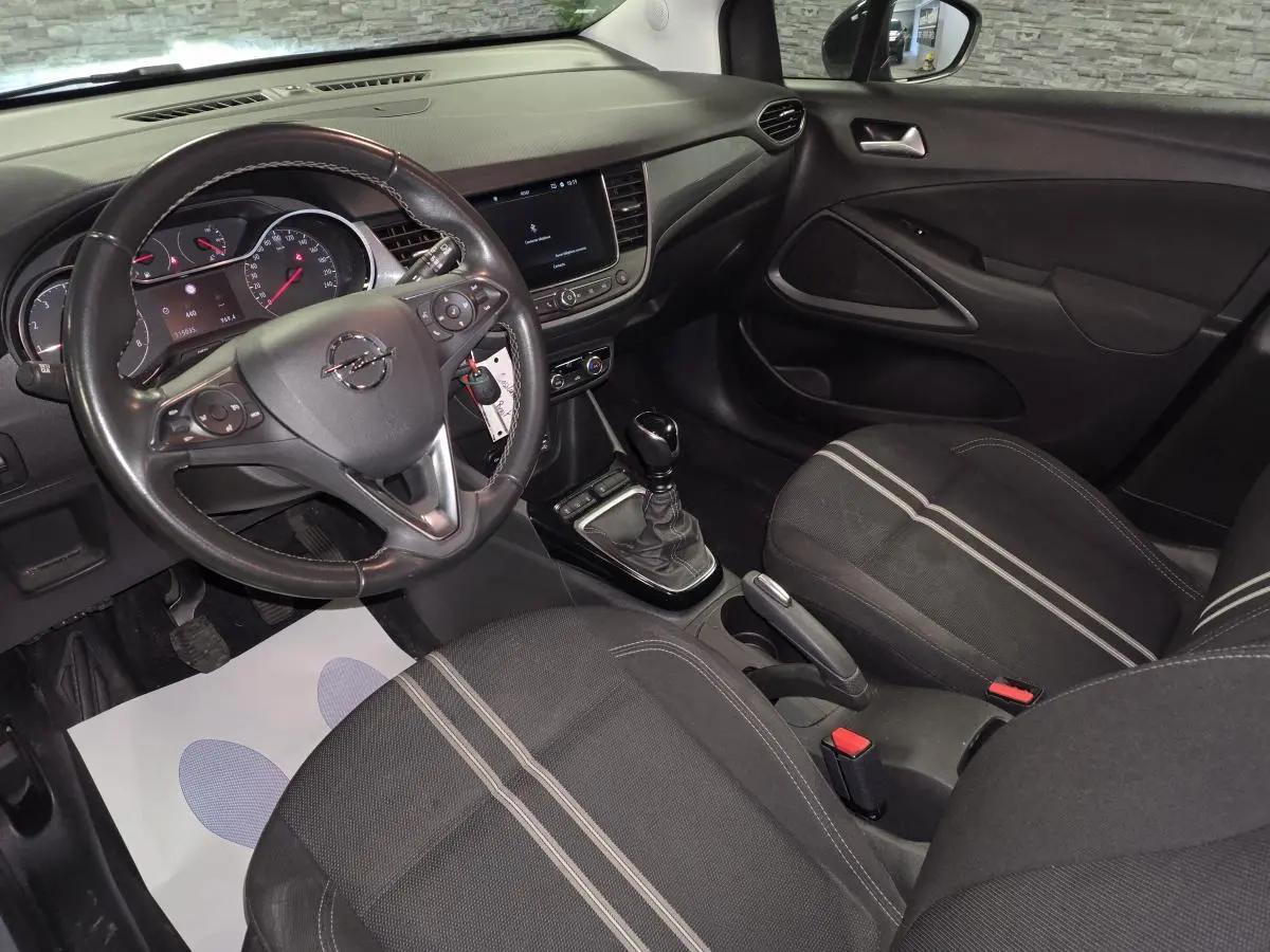 Vue intérieure côté conducteur de l'Opel Crossland 2023 avec sellerie tissu noire à bandes grises et tableau de bord noir.