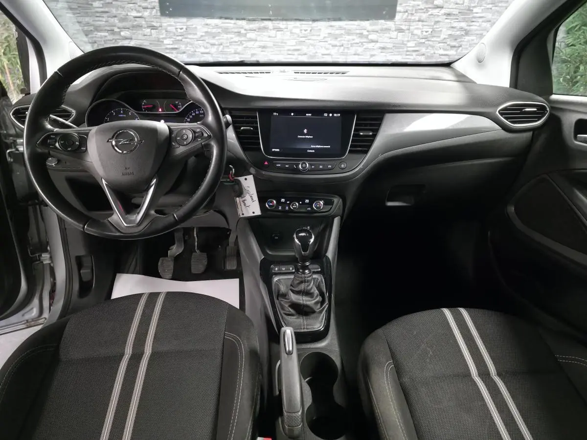 Intérieur avant de l'Opel Crossland gris 2023, vue centrée sur le tableau de bord et la boîte manuelle noire.