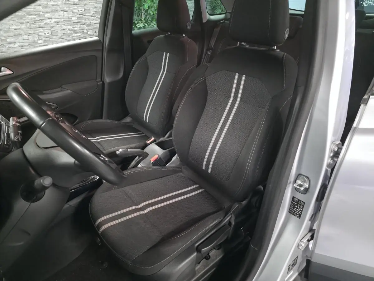 Vue intérieure côté conducteur de l’Opel Crossland gris 2023, avec sièges tissu noir à bandes grises et volant visible.