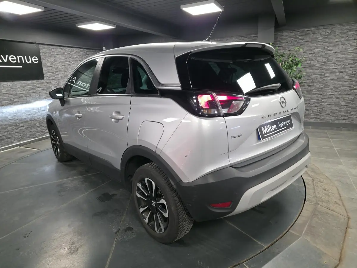 Opel Crossland gris métallisé vu en 3/4 arrière droit, avec jantes alliage noires et toit noir contrasté.