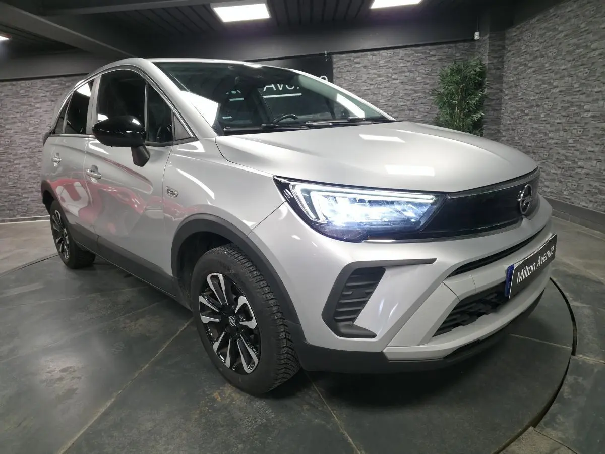 Opel Crossland gris métallisé en 3/4 avant droit, avec phares LED allumés et jantes alliage bicolores.