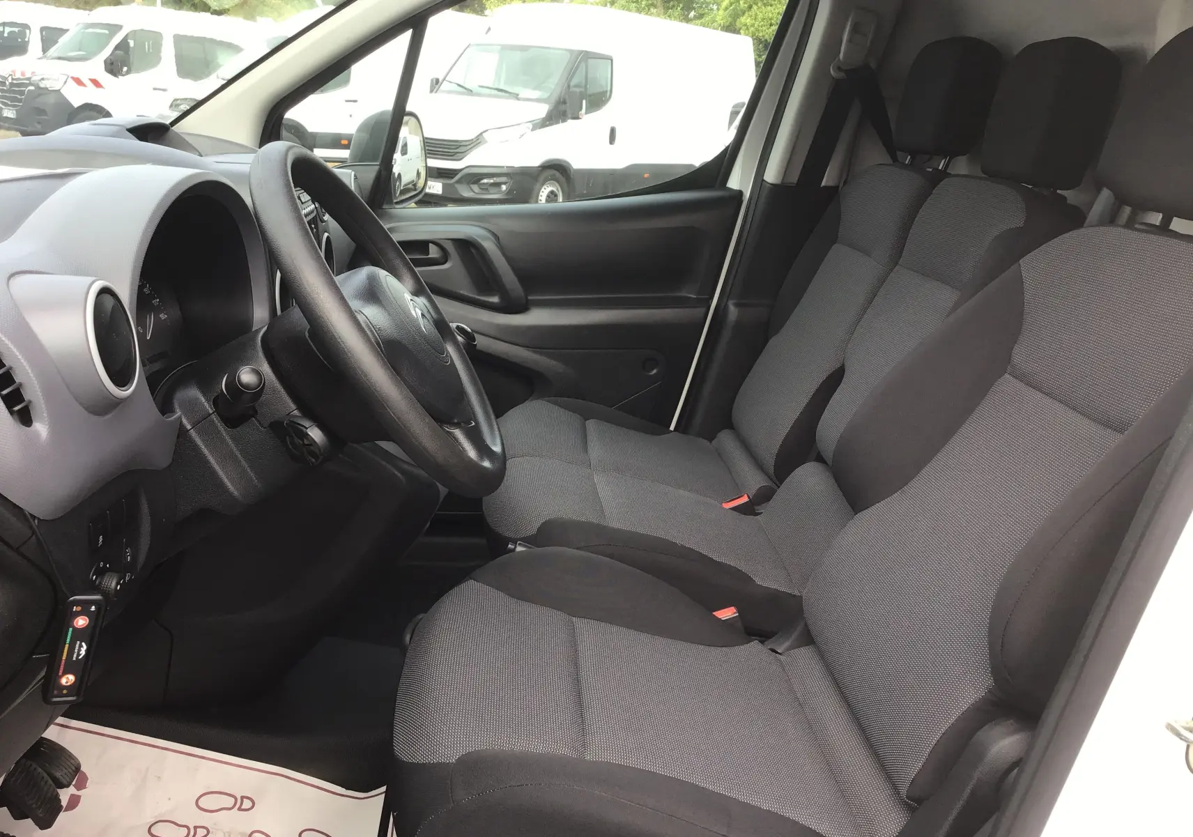 Vue intérieure côté conducteur du Citroën Berlingo XL blanc 2018, montrant les sièges tissu gris et le volant noir.