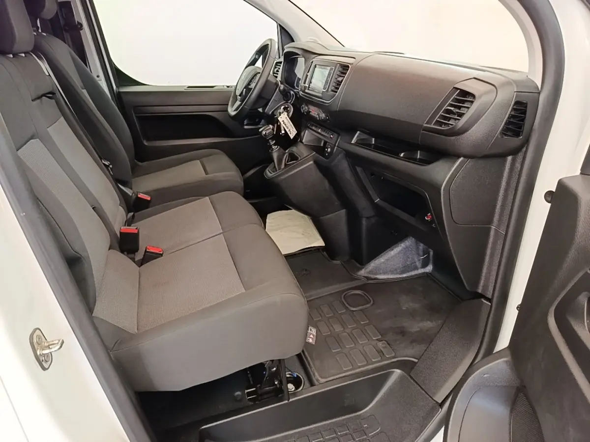 Vue intérieure côté conducteur du Peugeot Expert Fourgon blanc, montrant les sièges avant et le tableau de bord avec écran tactile.