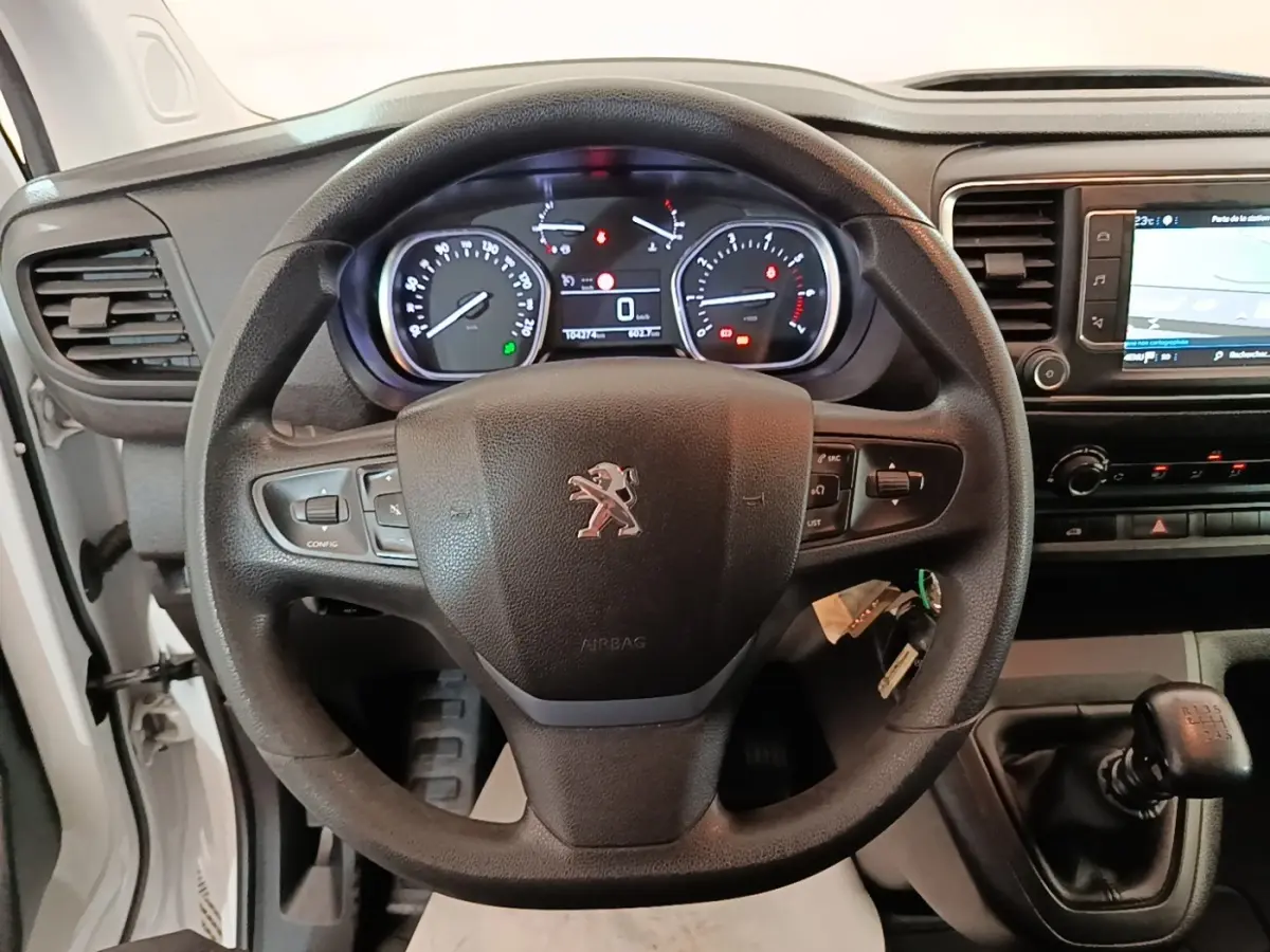 Vue intérieure centrée sur le volant Peugeot noir et le tableau de bord avec écran tactile du Expert Fourgon blanc.