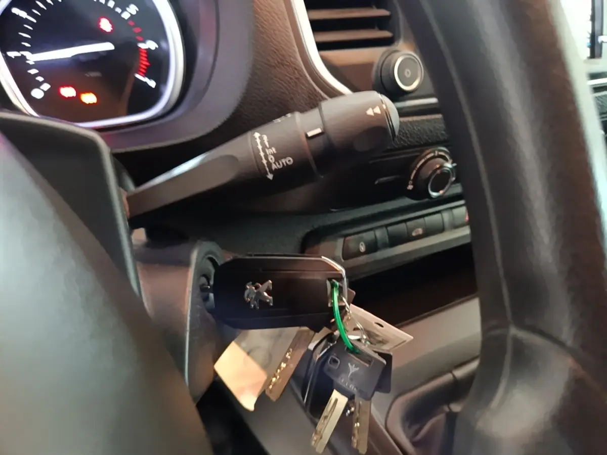 Gros plan sur le contact avec clé Peugeot insérée, volant noir et commandes du tableau de bord du Peugeot Expert Fourgon blanc.