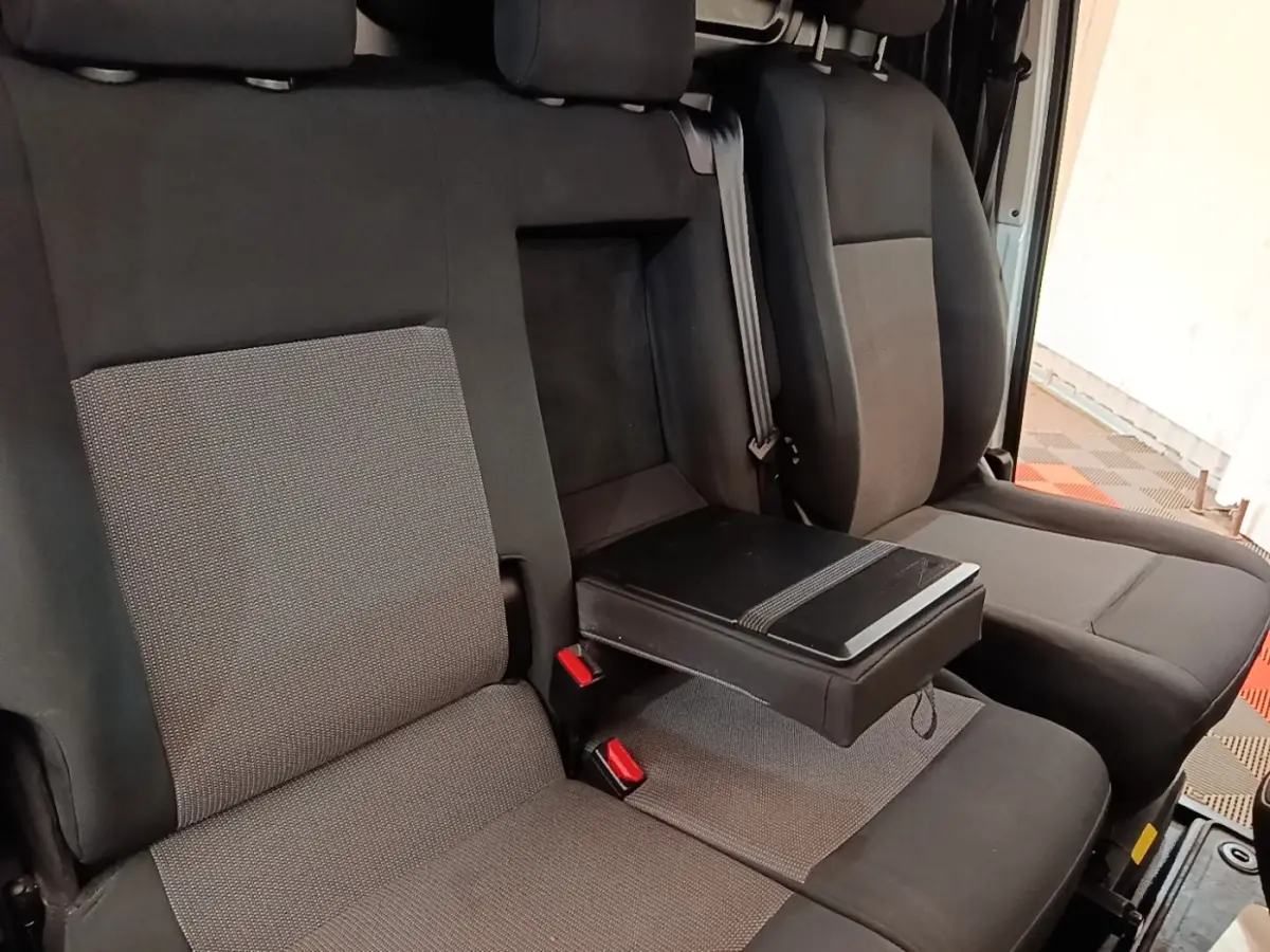 Vue rapprochée des sièges avant gris foncé et clair du Peugeot Expert Fourgon, avec accoudoir central déplié.