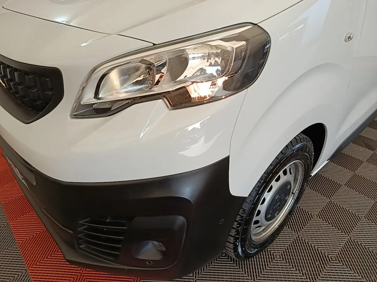 Gros plan sur l'avant droit blanc du Peugeot Expert Fourgon 2023, avec phare allumé et pare-chocs noir mat.