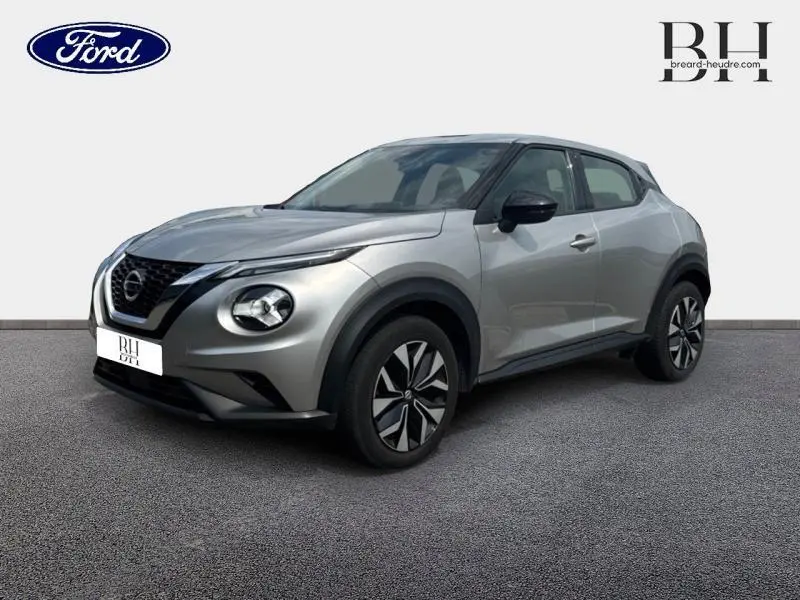 Nissan Juke 2023 gris perle métallisé vu en 3/4 avant droit, avec phares ronds et jantes au design moderne.