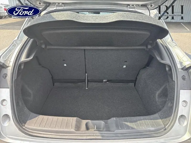 Coffre ouvert vu de l'arrière d'un Nissan Juke gris perle métallisé, montrant l'espace de chargement vide.