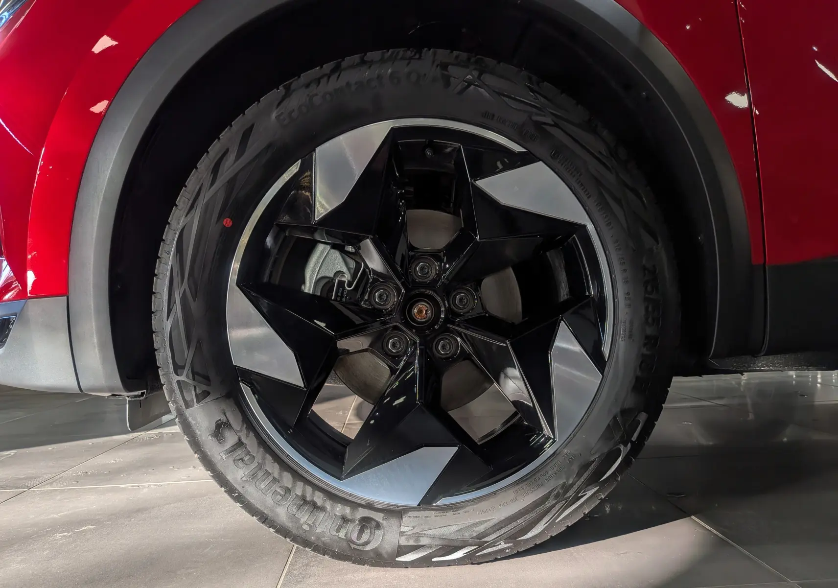 Gros plan sur la roue avant droite du Renault Captur E-TECH rouge Flamme avec jante noire et argentée au design géométrique.