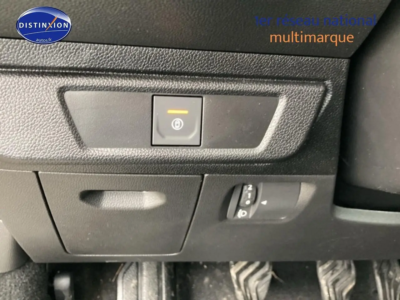Détail intérieur montrant le bouton de frein de stationnement électrique et les pédales du Dacia Jogger 2025.