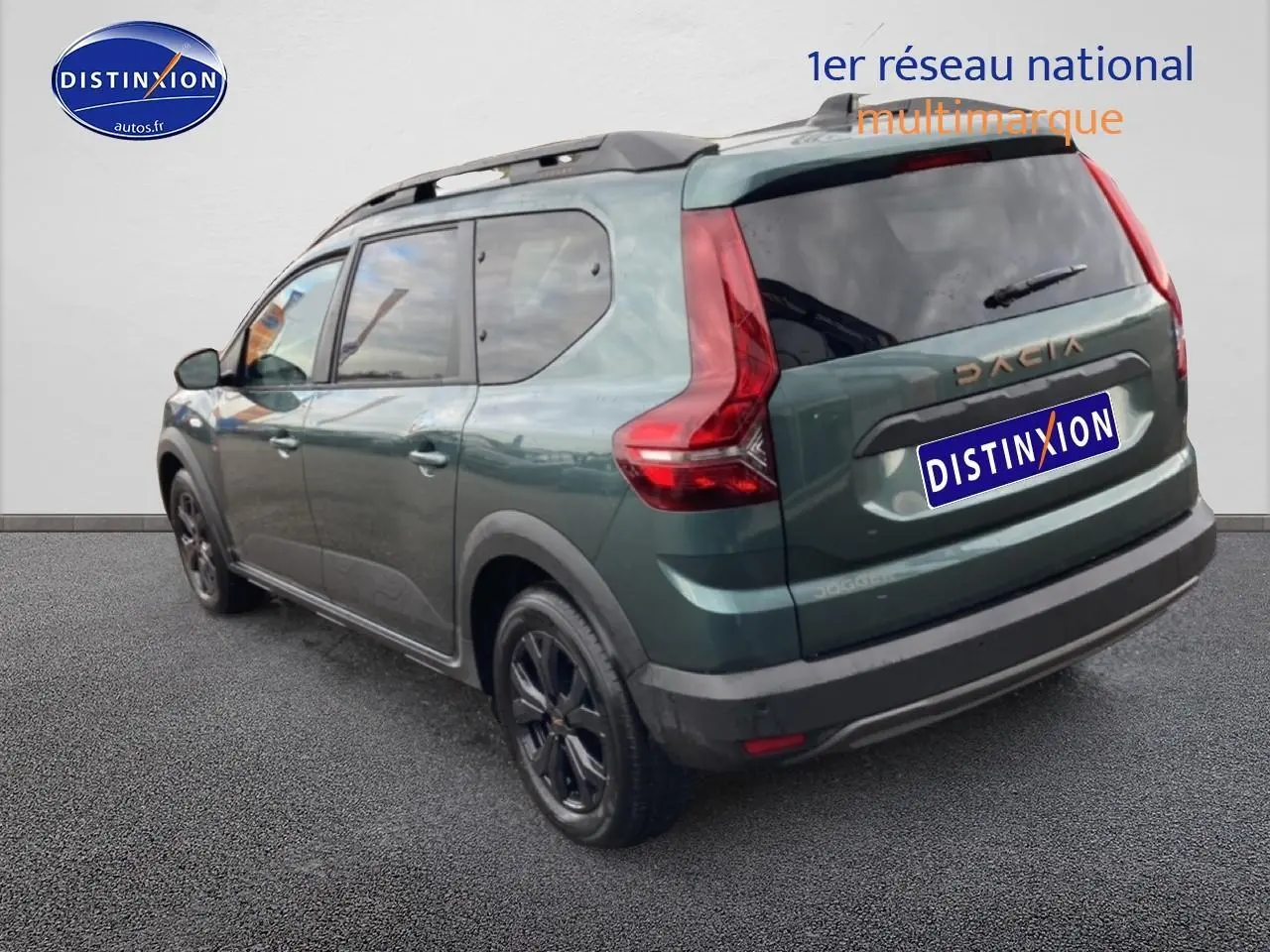 Vue 3/4 arrière droite d'un Dacia Jogger vert cèdre avec barres de toit et jantes noires.