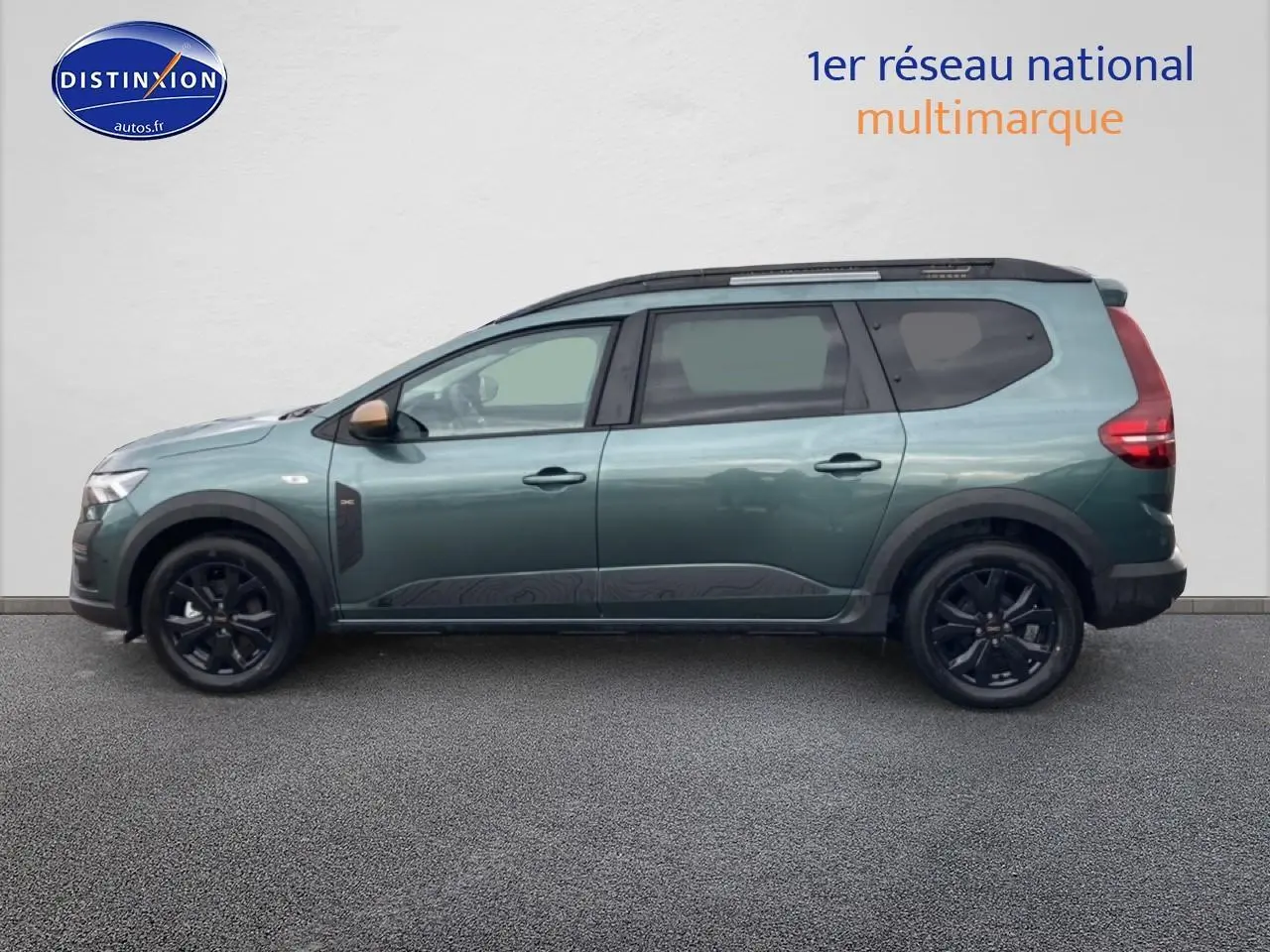 Vue de profil côté gauche d'un Dacia Jogger vert cèdre avec jantes noires et barres de toit.