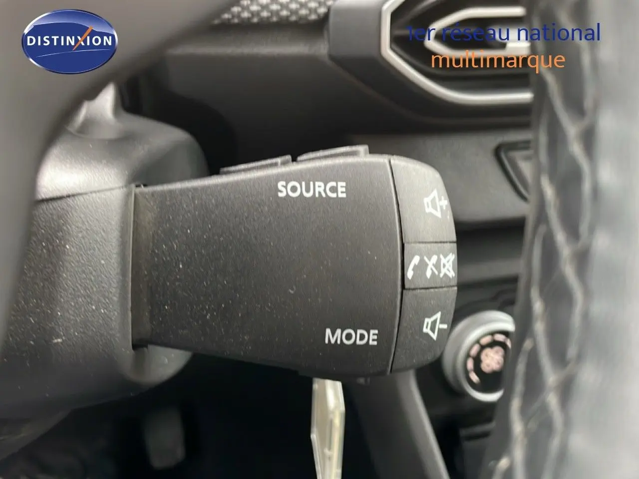 Gros plan sur la commande au volant du Dacia Jogger gris schiste, avec boutons source et mode visibles.
