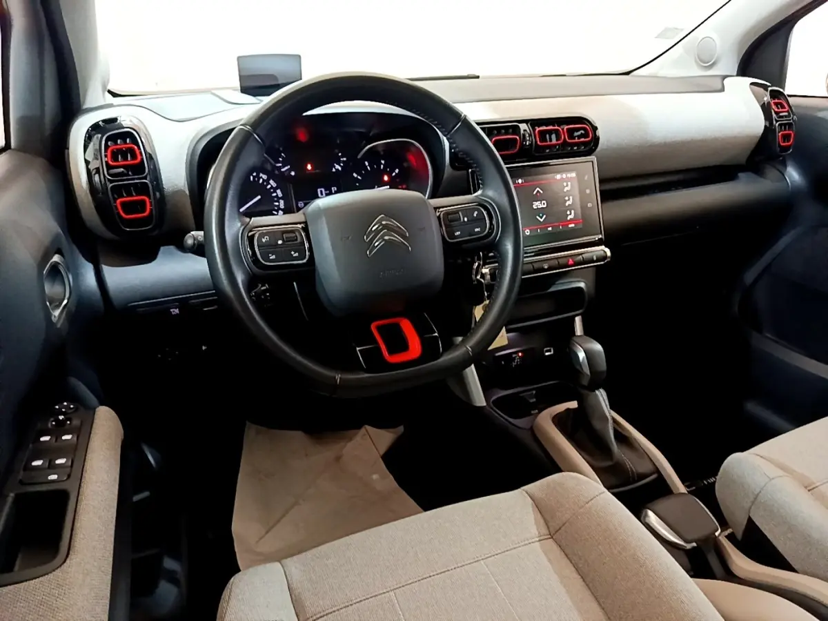 Intérieur de Citroën C3 Aircross 2020, vue du poste de conduite avec volant cuir noir et touches rouges sur aérateurs.