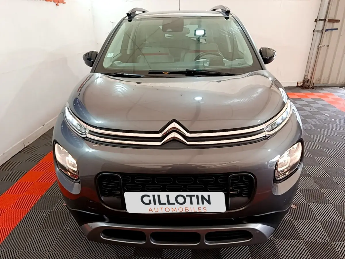 Vue avant d'un Citroën C3 Aircross gris foncé, avec calandre distinctive et phares allumés en intérieur.