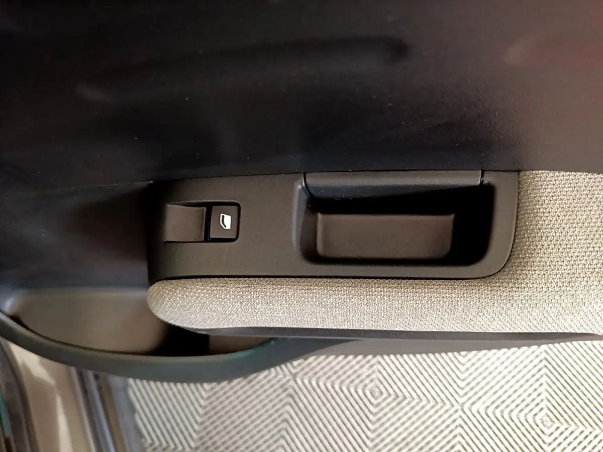 Détail de la commande de lève-vitre sur la porte intérieure côté conducteur d'une Citroën C3 Aircross gris foncé.