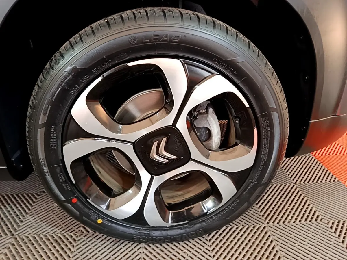 Gros plan sur la roue avant droite d'une Citroën C3 Aircross gris foncé avec jante alliage bicolore.