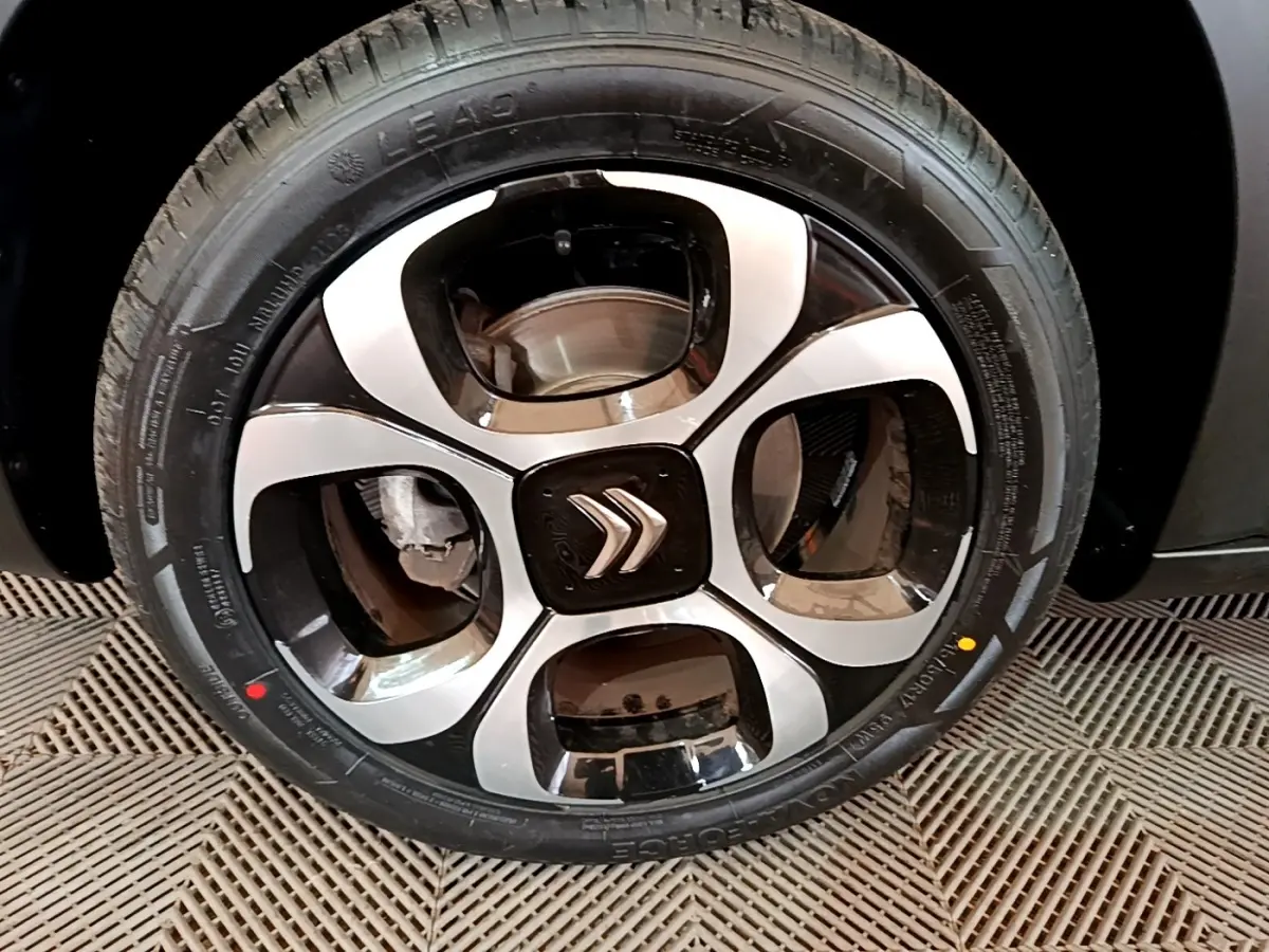 Gros plan sur la jante avant droite noire et argentée du Citroën C3 Aircross gris foncé, avec logo Citroën central.