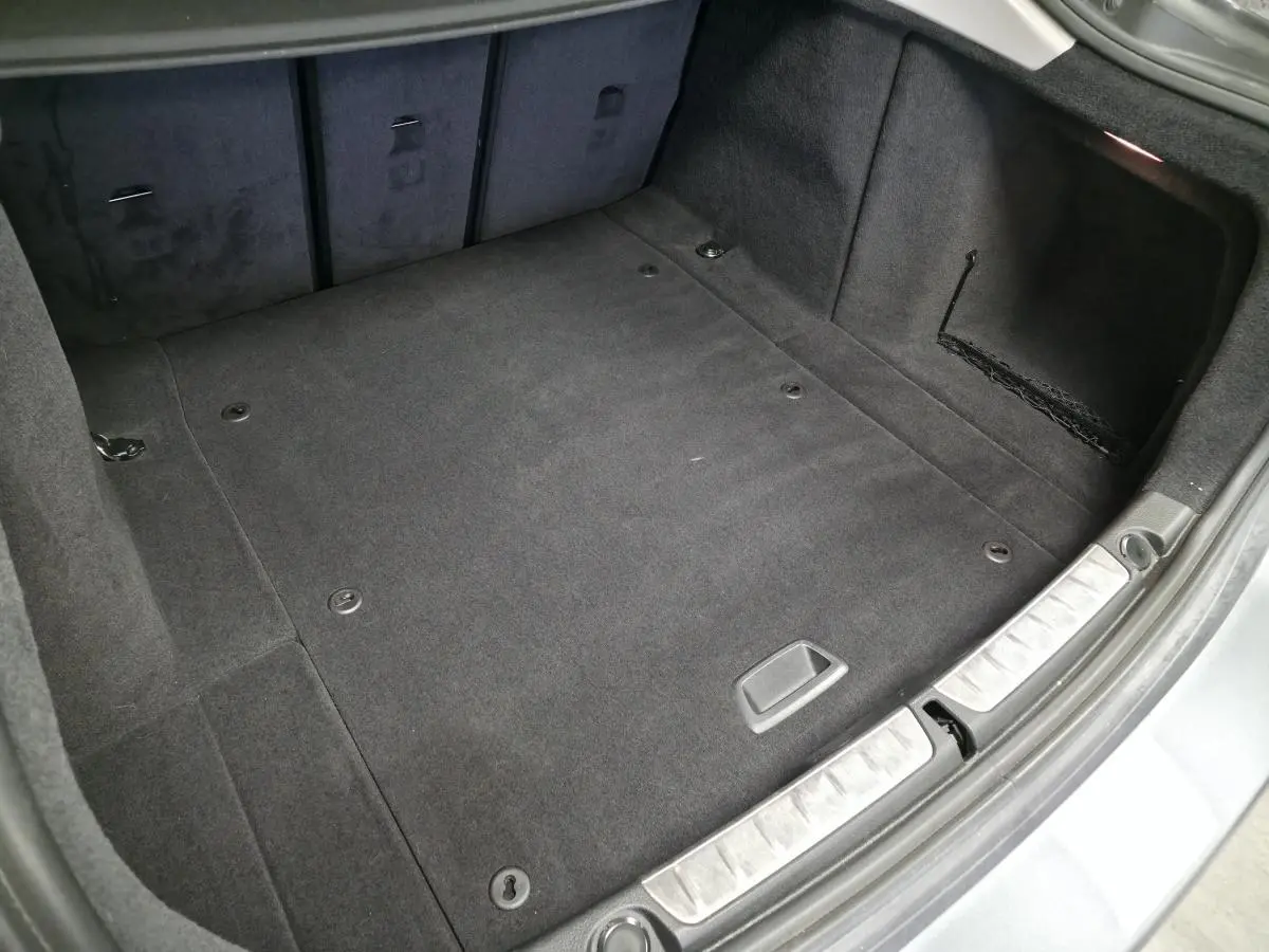 Vue intérieure du coffre spacieux et propre de la BMW Série 4 Gran Coupé gris foncé, avec tapis en tissu anthracite.
