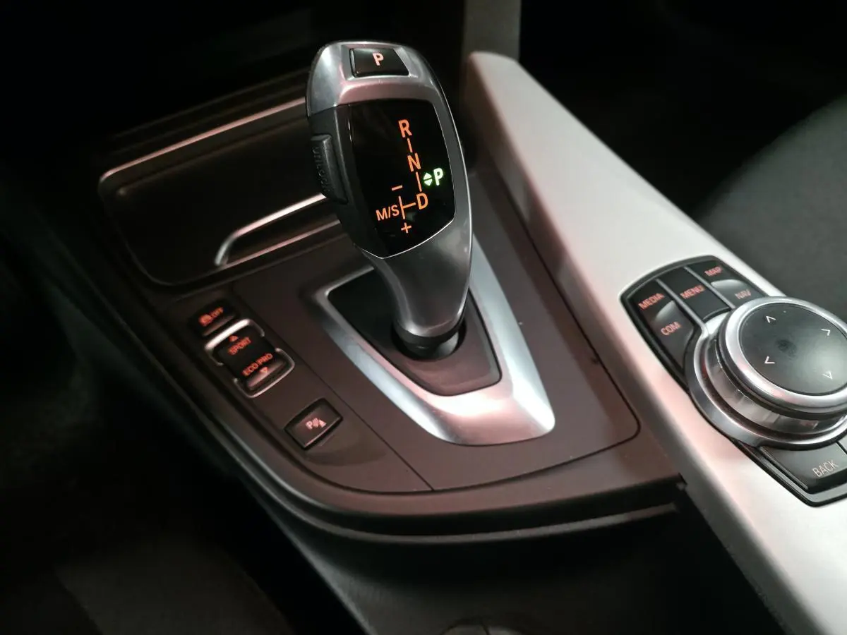 Le levier de vitesse automatique BMW gris satiné avec commandes de mode de conduite et molette iDrive sur console centrale.