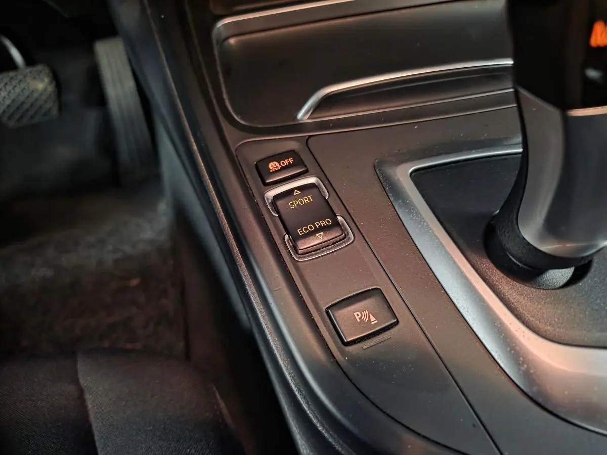 Gros plan sur la console centrale de la BMW Série 4 420d xDrive, boutons de mode conduite et radar de stationnement.