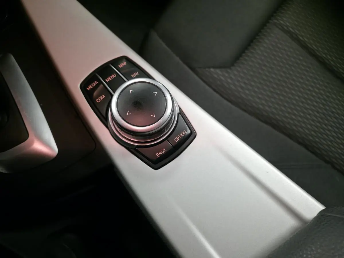 Gros plan sur la molette de commande iDrive et la console centrale aluminium satiné de la BMW Série 4 gris foncé.