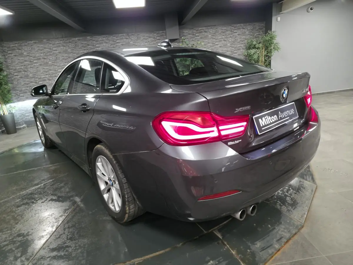 BMW Série 4 Gran Coupé gris foncé vue 3/4 arrière droit avec feux LED et double sortie d’échappement ronde à gauche.