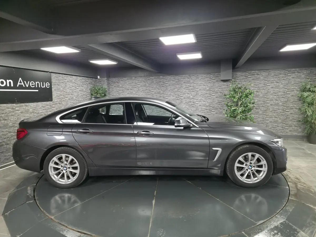 BMW Série 4 Gran Coupé gris foncé vue de profil côté gauche, avec jantes alliage et détails chromés.