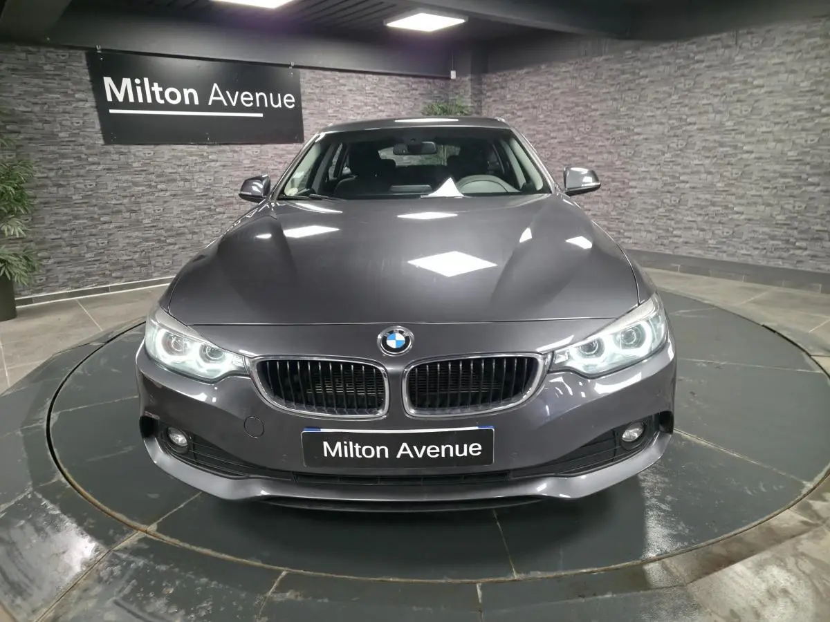 Vue avant d'une BMW Série 4 Gran Coupé gris foncé avec calandre double haricot et phares LED allumés.