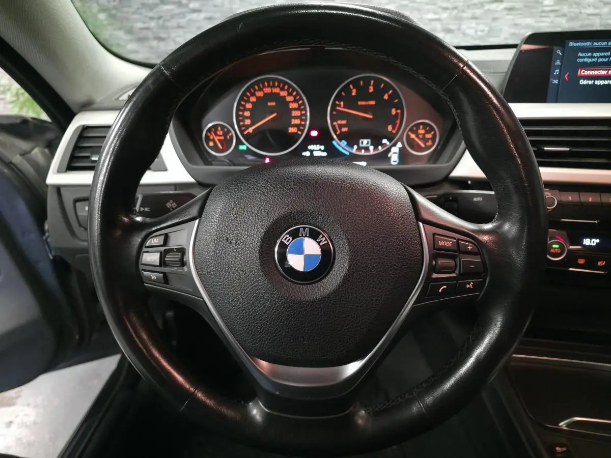 Vue intérieure centrée sur le volant cuir noir de la BMW Série 4 420d Gran Coupé avec tableau de bord et écran multimédia.