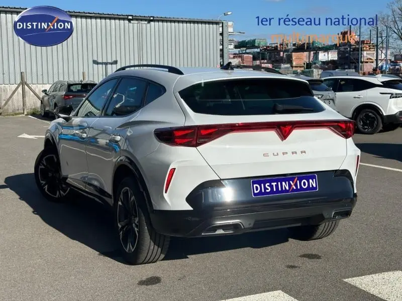 Vue 3/4 arrière droite d'un CUPRA Formentor blanc Nevada métallisé avec feux arrière reliés et jantes noires.