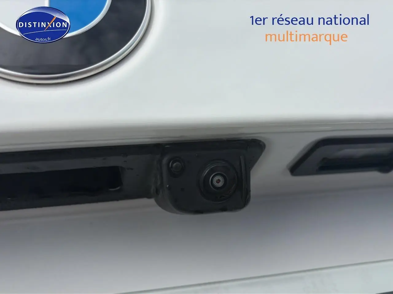Gros plan sur la caméra de recul noire intégrée à l'arrière d'une BMW Série 1 blanche pure.