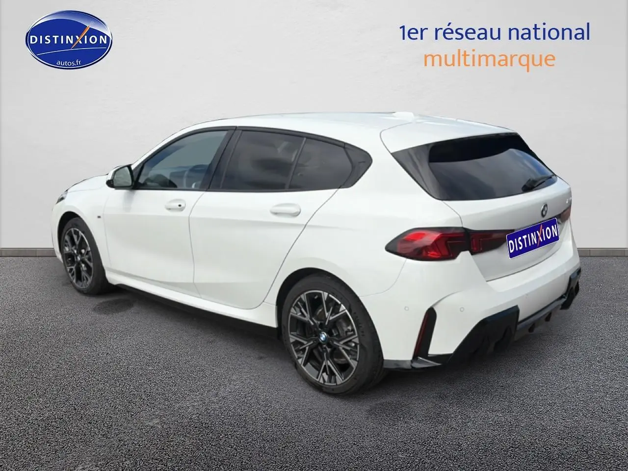 BMW Série 1 blanche vue en 3/4 arrière droit, avec jantes sport noires et vitres teintées.