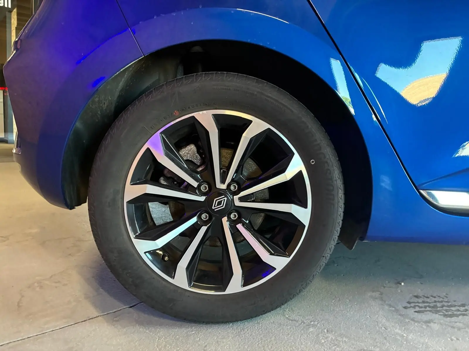 Gros plan sur la roue arrière droite d'une Renault Clio V E-TECH 145 TECHNO bleu iron avec jante alliage bicolore.