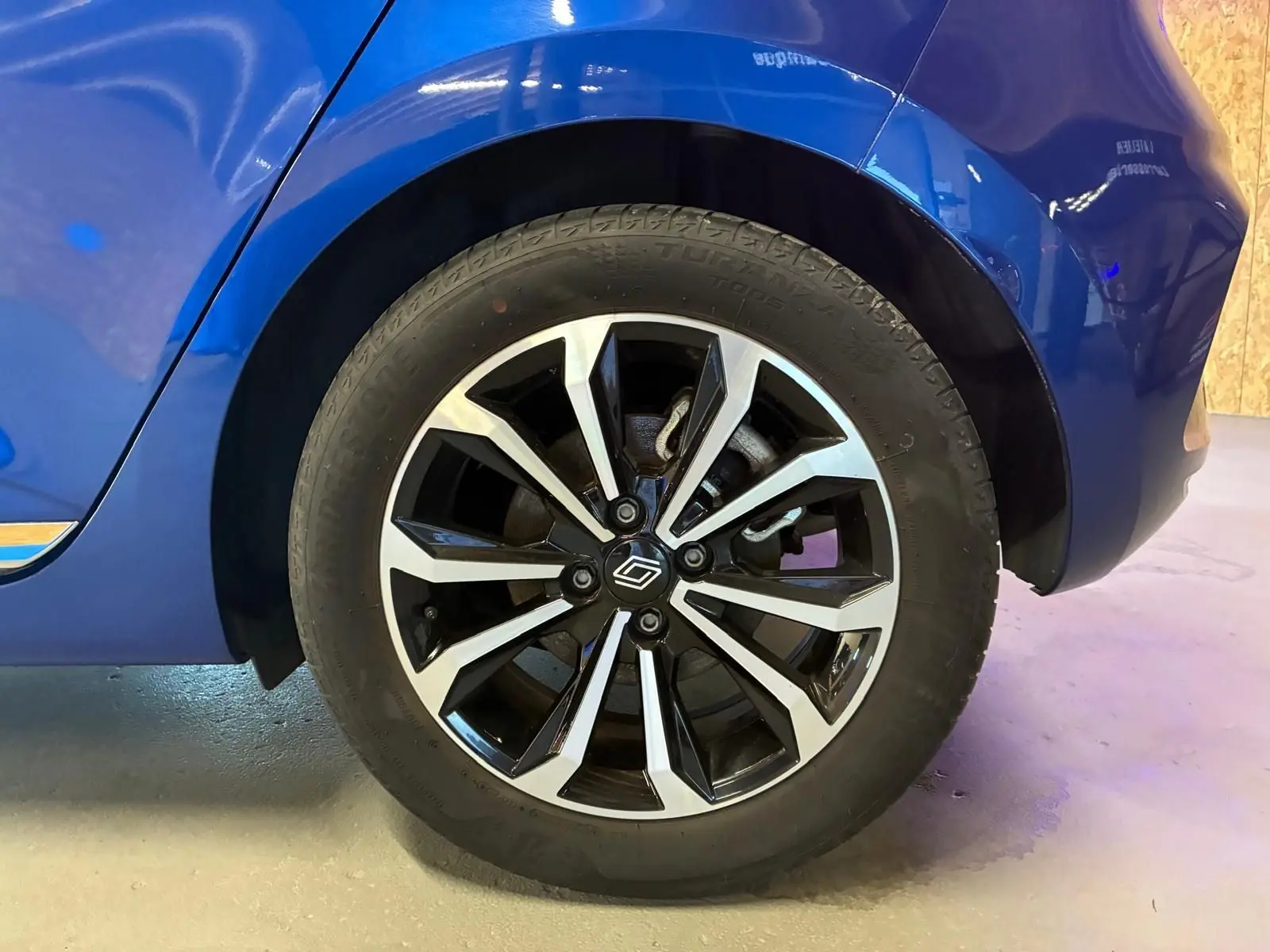 Gros plan sur la roue arrière droite de la Renault Clio V E-TECH 145 TECHNO bleu iron avec jante alliage bicolore.