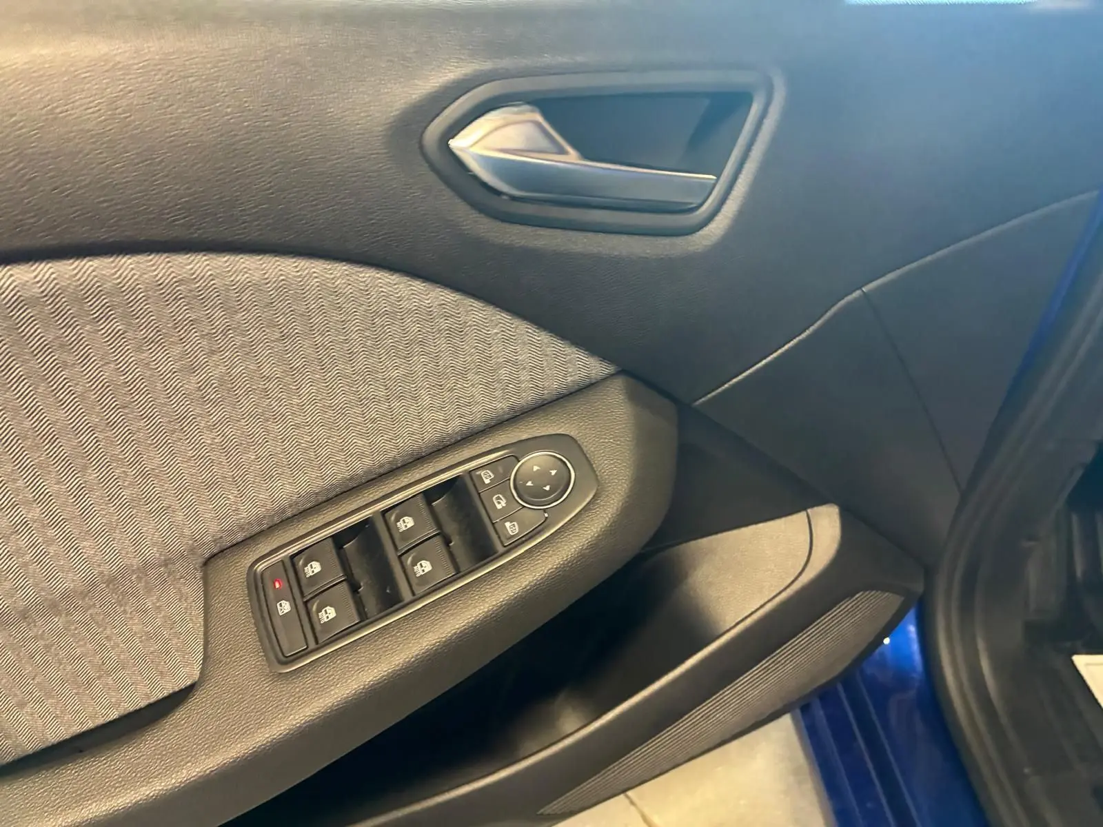 Détail de la porte côté conducteur de la Renault Clio V E-Tech 145 Techno bleu Iron, avec commandes des vitres et poignée intérieure.